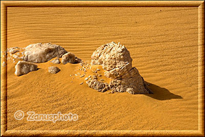 Steine und Kristallgebilde im Sand der Sahara