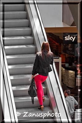 Frau in rot auf Rolltreppe