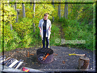 Frau grillt Steaks am Lagerfeuer