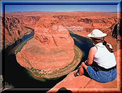 Am Horseshoe Bend nahe Page sitzt eine Frau am Rand des Colorado River Canyon