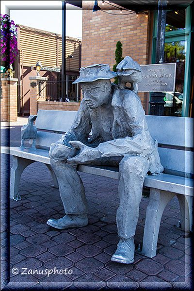 Skulptur eines Mannes auf einer Bank