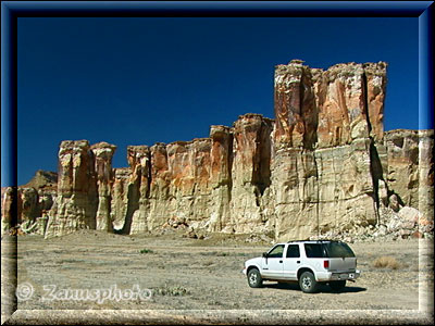 Riesige Felswand mit im Vordergrund parkendem Jeep